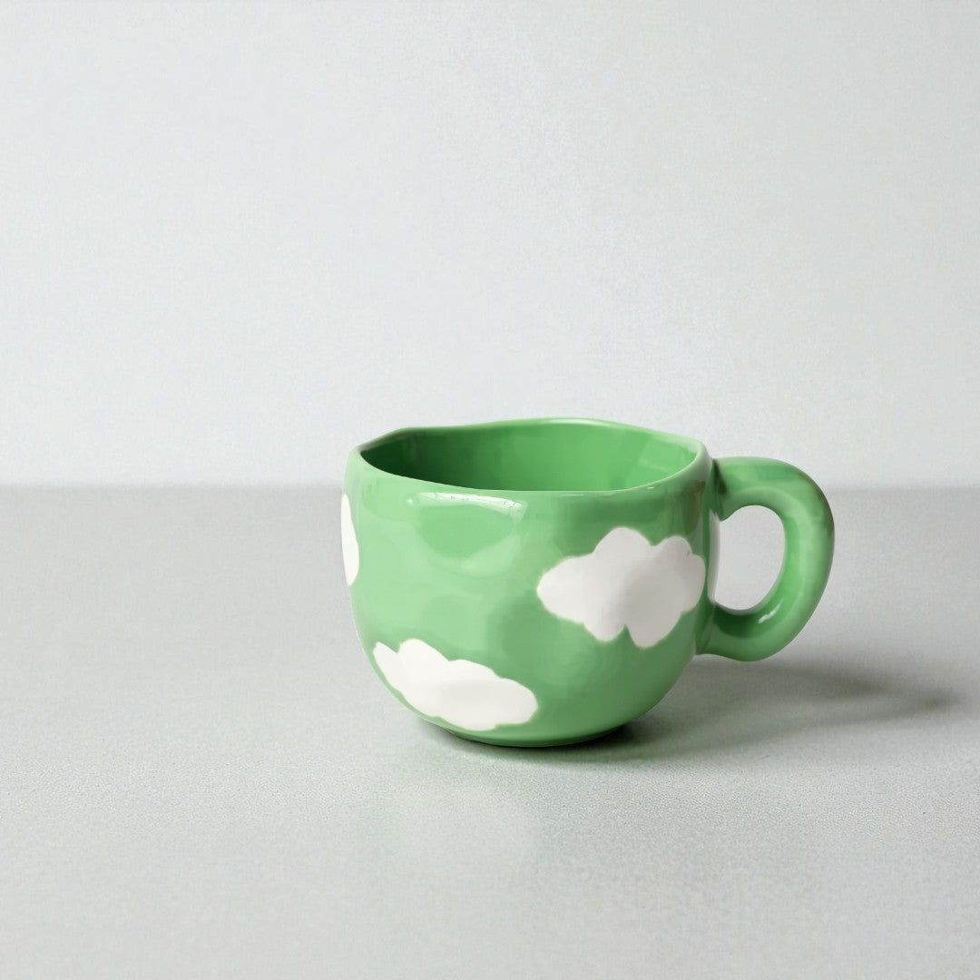 Green mug with white cloud designs on a light gray background