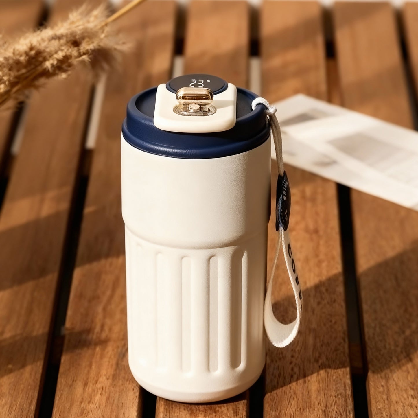 White stainless steel tumbler by Lunari Haus with a muted blue lid on a warm wooden surface in soft natural light.